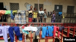 Children stand behind a fence at a school to which they have been evacuated from a village near Hodeida airport amid fighting between government forces and Houthi fighters in Hodeida, Yemen, June 17, 2018. 