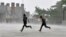 Men run for cover during a heavy rain shower in the northern Indian hill town of Shimla, July 4, 2014.