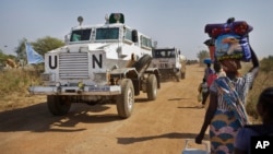 FILE - Displaced people are passed by a United Nations vehicle while walking towards a U.N. camp in Malakal, South Sudan, Dec. 30, 2013.