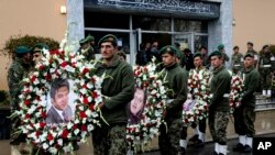 Petugas pengawal kehormatan Afghanistan membawa karangan bunga dengan foto wartawan kantor berita Perancis AFP Sardar Ahmad, istri dan kedua anaknya.