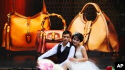 FILE - A couple pose for photos in front of a luxury shop in Hanoi, Vietnam.