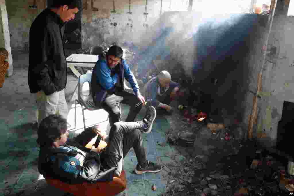 گروهی از مهاجران با روشن کردن آتش در یک ساختمان متروکه در بوسنی، خود را گرم می‌کنند