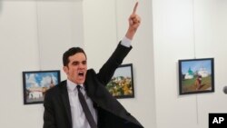 A gunman gestures after shooting the Russian Ambassador to Turkey, Andrei Karlov, at a photo gallery in Ankara, Turkey, Monday, Dec. 19, 2016.