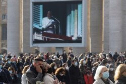 Fieles católicos reunidos en la Plaza de San Pedro, en Roma, para el rezo del Angelus, el domingo 20 de diciembre de 2020. En una pantalla, una imagen del papa Francisco rezando la plegaria en la ventana de su biblioteca.