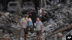 Los residentes caminan sobre los escombros de los edificios destruidos con sus pertenencias en el lugar del ataque aéreo israelí del jueves, en Beirut, Líbano, el viernes 11 de octubre de 2024. AP