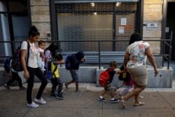 FILE - Children cover their faces as they are escorted to the Cayuga Center, which provides foster care and other services to immigrant children separated from their families, in New York, July 10, 2018.