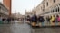 People walk on a catwalk in a flooded Saint Mark Square during a period of seasonal high water in Venice, Italy, Oct. 29, 2018 