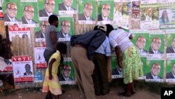 FILE: Residents of Epworth peep through a hole while watching a street performance a day before elections, Harare, July,30, 2013. 