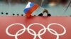 Seorang penonton memegang bendera Rusia di atas foto Cincin Olympiade di Adler Arena Skating Center di Olimpiade Musim Dingin di Sochi, Rusia, 18 Februari 2014. (Foto: David J. Philip/AP)