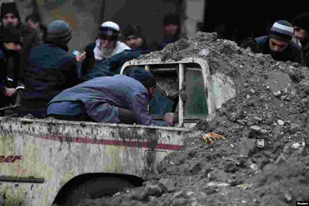 A man looks for survivors inside a pickup truck at a damaged site after what activists said was an airstrike by forces loyal to Syrian President Bashar al-Assad in Duma, Damascus. 