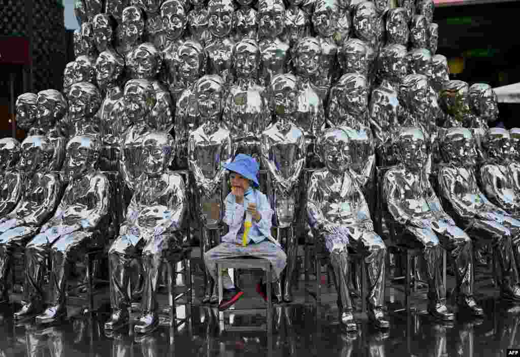 A boy sits on a chair amid sculptures on display at a shopping center, on International Children&#39;s Day, in Beijing. China announced it would allow couples to have three children.