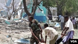 Tentara Somalia dan warga membawa korban tewas di lokasi ledakan bom mobil di Mogadishu (4/10).