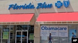 FILE - A man walks by a health care insurance office advertising the Affordable Care Act, also known as 'Obamacare,' in Hialeah, Florida, July 27, 2017.
