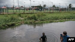 FILE - A boy stands waist deep in water that surrounds houses next to the Clara Town Survivors Sports Park in Clara Town, Monrovia on October 6, 2023.