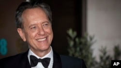 FILE - Richard E Grant poses for photographers upon arrival at the BAFTA Film Awards after party in London on Feb. 2, 2020.