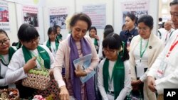 La entoces líder de Myanmar, Aung San Suu Kyi, en el centro, mira una canasta casera exhibida durante una reunión en el Centro Internacional de Convenciones de Myanmar, el martes 28 de enero de 2020.