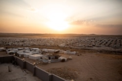In this Aug. 24, 2019 photo, the sun sets over Sharia Camp, where Yazidis displaced by Islamic State militants are housed near Dohuk, Iraq.