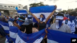 Los manifestantes antigubernamentales marchan frente a la Universidad Centroamericana (UCA) en Managua, Nicaragua.