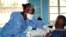 FILE - A health care worker from the World Health Organization, left, gives an Ebola vaccination to a front line aid worker who will then vaccinate people who might potentially have the virus, in Mbandaka, Congo, May 30, 2018.