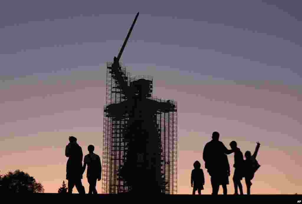 People walk near the statue &#39;The Motherland Calls&#39; under reconstruction in Mamayev Kurgan, the main place of the Battle of Stalingrad memorial, during sunset in Volgograd, Russia, Aug. 12, 2019.