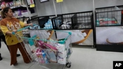 FILE —A shopper guides her cart past sugar shelves at a supermarket in Bangkok, Thailand, November 9, 2023. In Thailand, El Nino effects early in the growing season altered not just the quantity but also the quality of the harvest.