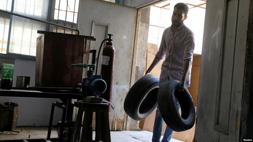 Engineering student Mohamed Amr carries car tires to be used in extracting fuel in Cairo, Egypt, Aug. 23, 2017. 