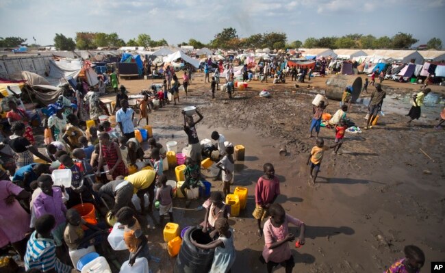 FILE - Displaced people gather around a water truck to fill containers at a United Nations compound which has become home to thousands of people displaced by the recent fighting, in the capital Juba, South Sudan, Dec. 29, 2013.