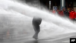 Manifestant ciblé par un canon à eau lors d'affrontements avec la police anti-émeute à Bruxelles, Belgique, le 24 mai 2016.