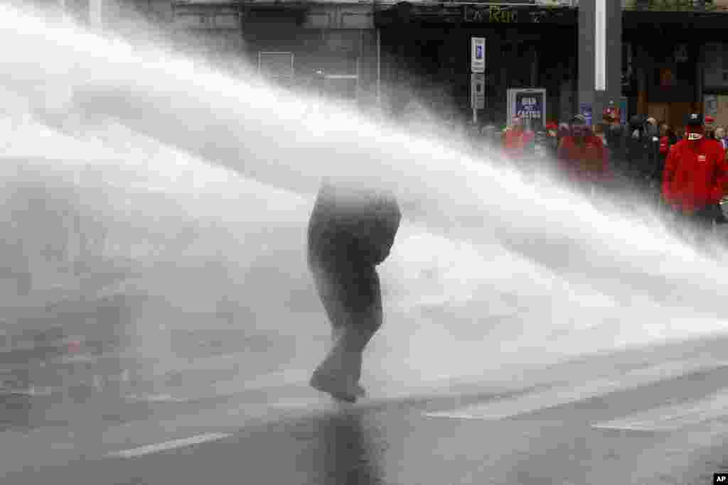 A protester is hit by a water cannon during a demonstration against new working regulations in Brussels, Belgium.