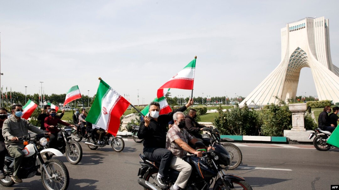 Warga Iran mengibarkan bendera nasional mereka saat ikut dalam pawai di alun-alun Azadi (Kebebasan) ibu kota Teheran, menandai hari al-Quds (Yerusalem), 7 Mei 2021. (Foto: STR / AFP)