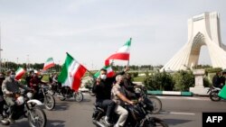 Warga Iran mengibarkan bendera nasional mereka saat ikut dalam pawai di alun-alun Azadi (Kebebasan) ibu kota Teheran, menandai hari al-Quds (Yerusalem), 7 Mei 2021. (Foto: STR / AFP)