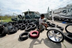 Cameron Arvie, 11, climbs on tires strewn by Hurricane Laura, at the family's destroyed auto detailing business in Lake Charles, La., Aug. 30, 2020.