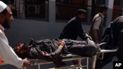 Pakistani volunteers push a stretcher carrying an injured paramilitary soldier at a hospital after a huge suicide bomb attack on the US consulate in Peshawar on 5 Apr 2010