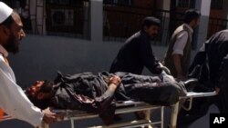 Pakistani volunteers push a stretcher carrying an injured paramilitary soldier at a hospital after a huge suicide bomb attack on the US consulate in Peshawar on 5 Apr 2010