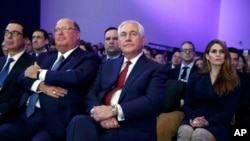 Secretary of State Rex Tillerson, center, Treasury Secretary Steven Mnuchin, left and White House Communications Director Hope Hicks, right, listen as President Donald Trump delivers a speech to the World Economic Forum, Friday, Jan. 26, 2018, in Davos.