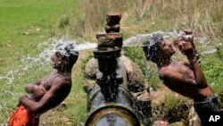 FILE - Slum dwellers bathe in water gushing out of a leakage from a pipe on the outskirts of Bhubaneswar, India, May 2, 2013. 