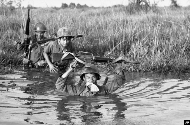 FILE - In this March 11, 1972 file photo, a South Vietnamese soldier holds his personal belongings in a plastic bag between his teeth as his unit crosses a muddy Mekong Delta stream in Vietnam near the Cambodian border. His unit was charged with stemming Communist infiltration from Cambodia into South Vietnam in the heavily populated Mekong Delta area. (AP Photo/Nick Ut)