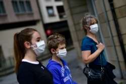 A family wearing face mask to protect of the coronavirus go for a walk, in Pamplona, northern Spain, April 27, 2020.
