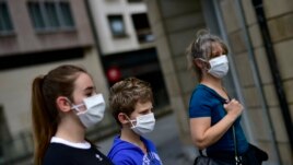 A family wearing face mask to protect of the coronavirus go for a walk, in Pamplona, northern Spain, Sunday, April 27, 2020. On Sunday, children under 14 years old will be allowed to take walks with a parent for up to one hour.