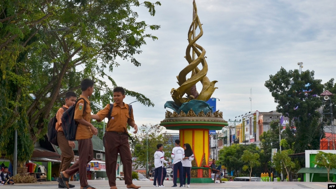 Beberapa pelajar bermain dekat Tugu Antikorupsi di Pekanbaru, Riau, 9 November 2017. (Foto: AFP)