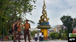 Beberapa pelajar bermain dekat Tugu Antikorupsi di Pekanbaru, Riau, 9 November 2017. (Foto: AFP)