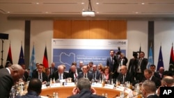 Members of the international committee take their seats for a follow-up meeting on Libya, arranged by German Foreign Minister Heiko Maas, in Munich, Germany, Feb. 16, 2020. 