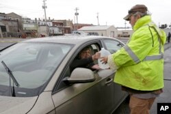 Jeff Vonder, right, an employee of Omaha's Municipal Utilities District, hands Kim O'Connor of Pacific Junction, Iowa, a jug of water he had filled from MUD's emergency water supply tanker, in Glenwood, Iowa, April 3, 2019.