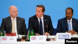 Britain's Prime Minister David Cameron (C) sits with Foreign Secretary William Hague (L) and Somali President Hassan Sheikh Mohamud, as he speaks at the Somalia conference in London, May 7, 2013. 