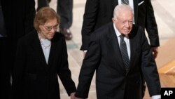 FILE - Former President Jimmy Carter, right, and his wife, former first lady Rosalynn Carter, hold hands as they walk from a state funeral for former President George H.W. Bush at the National Cathedral, December 5, 2018, in Washington.