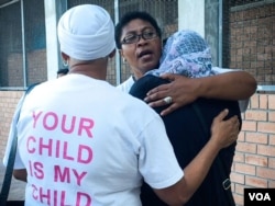 Women console each other outside the site of Zinadene Pelton's funeral. Some wear 'Your Child Is My Child' T-shirts to show solidarity. (Adams FitzPatrick/VOA) Click on photo for related video.