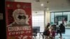 Women sit near a COVID-19 sign in a departure terminal at Juanda international airport in Surabaya, East Java, on April 24, 2020.