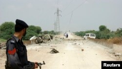 A policeman stands guard at the site of a roadside bomb outside Dera Ismail Khan, northwest Pakistan, Aug. 4, 2014. 