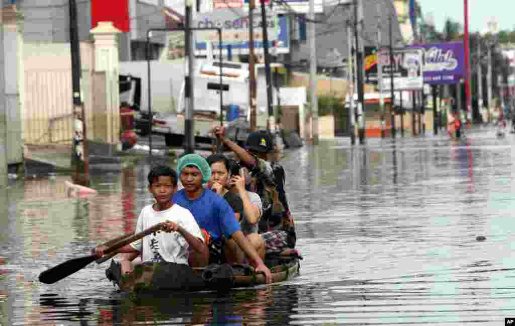 Local residents ride on a bamboo raft in a flooded street in northern Jakarta, Indonesia. Government officials have downplayed predictions that heavy rain and rising tides due to the full moon could cause the worst flood in the past six years.