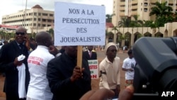 FILE - A Cameroonian journalist holds a sign reading "No to the persecution of journalists" during a free speech rally in Yaounde, Cameroon.